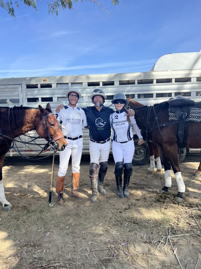 Facundo, Daniel Fernández and Rebecca Clark in polo whites beside two horses.